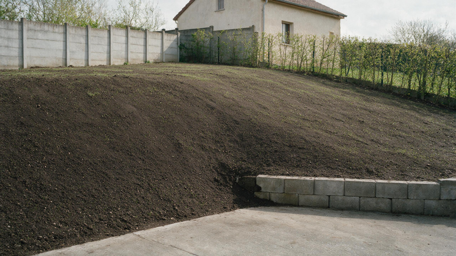 Modelovaný svah zahrady s ornicí a opěrnou zídkou z betonových tvárnic